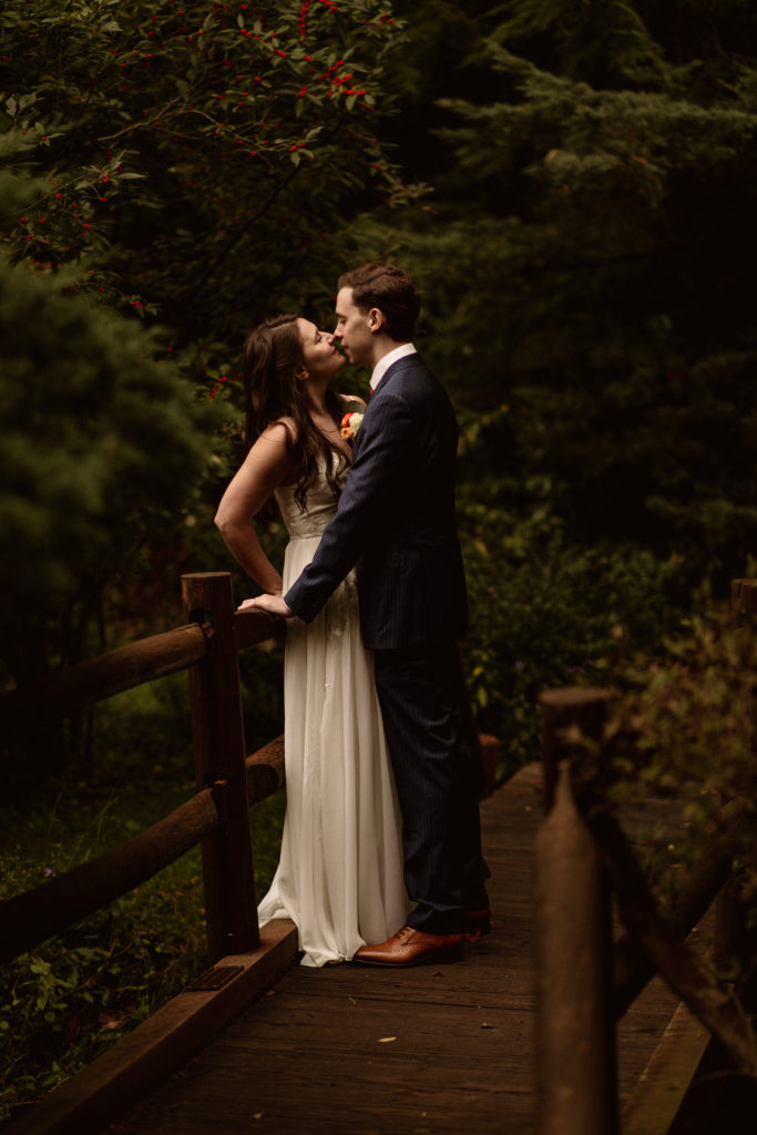Couple kissing on bridge in arboretum