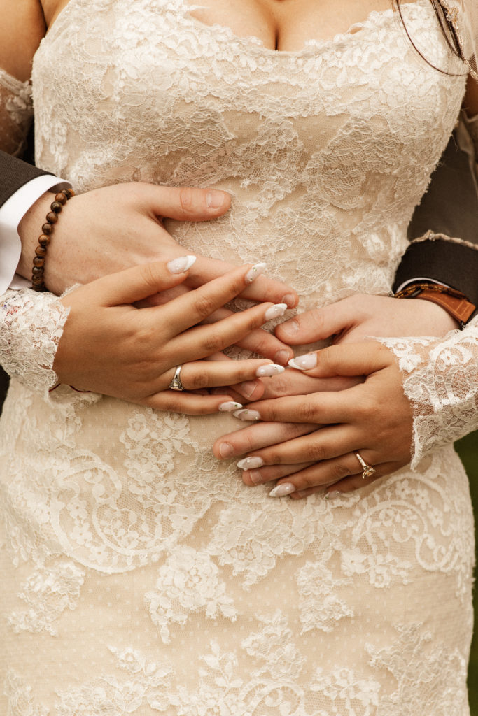 bride and groom hands on wedding dress