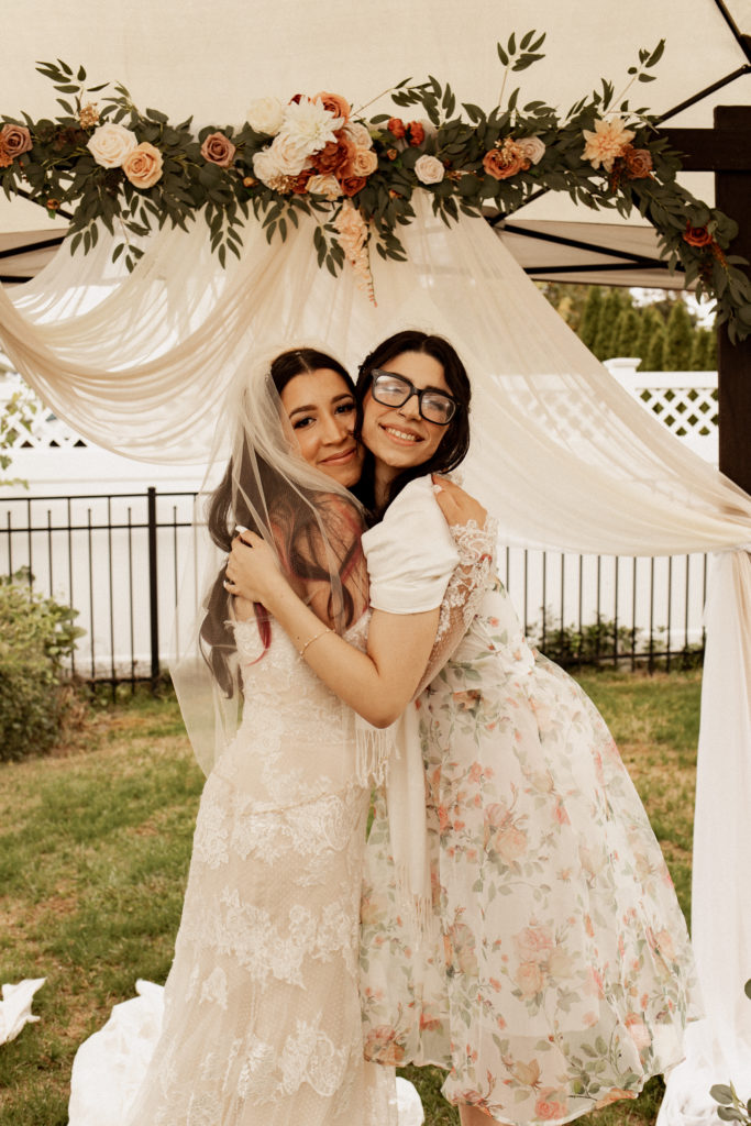 sister hugging the bride at her backyard wedding