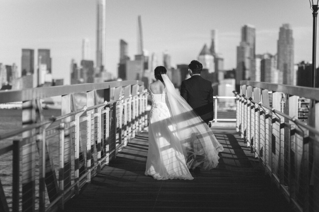 Bride and groom holding hands and walking together with the city skyline. NJ intimate wedding photographer for small, intimate weddings.
