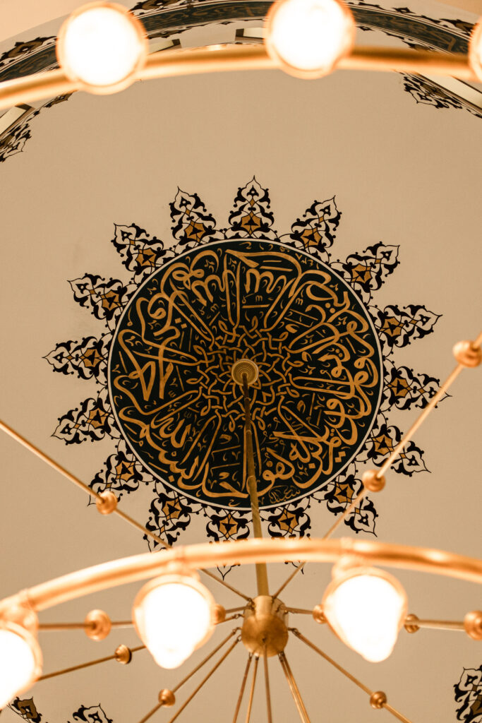 Detailed view of the mosque ceiling, featuring Arabic calligraphy from the Holy Qur’an.