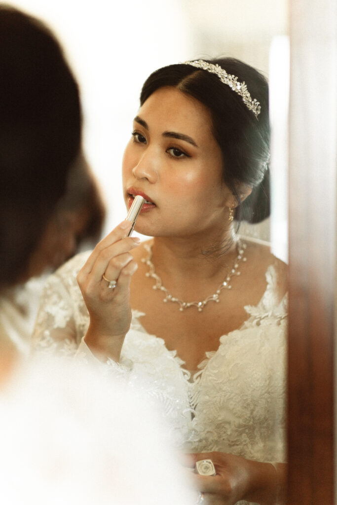 Bride applying lipstick. New Jersey bridal photography by an NJ Micro Wedding Photographer.
