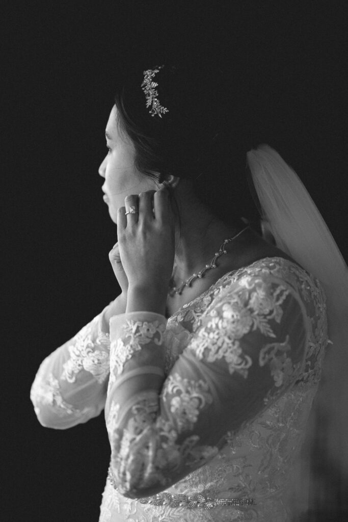 Black and white photo Bride putting on earrings. NJ wedding photojournalist capturing intimate wedding photography moments.
