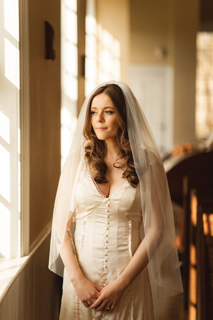 Bride in natural light, reflecting on the moment before the ceremony.
