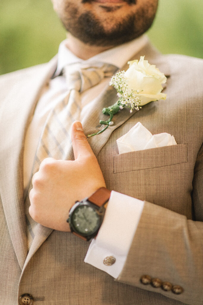 Close-up of the groom’s watch and boutonniere, emphasizing the attention to detail in Mo’s wedding outfit.
