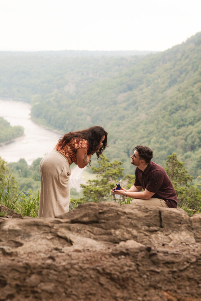 Jac is overcome with emotion as Alec proposes, with a panoramic view of the mountains and river in the background