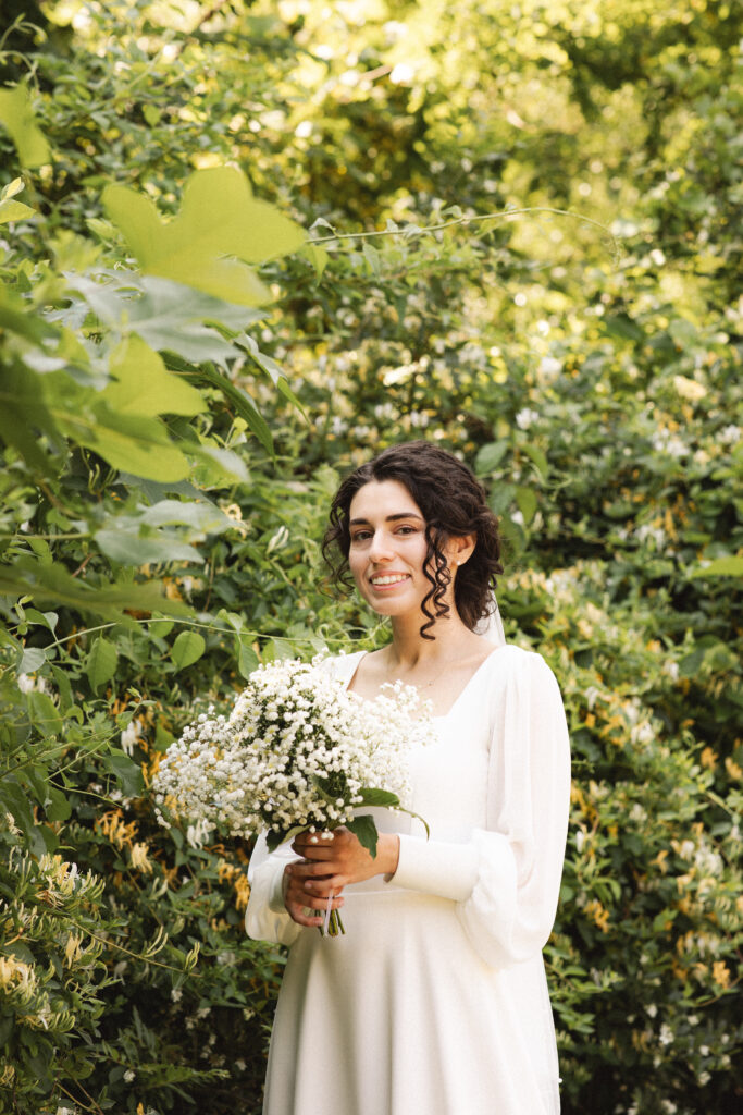 Bride smiling and holding a bouquet of white flowers.