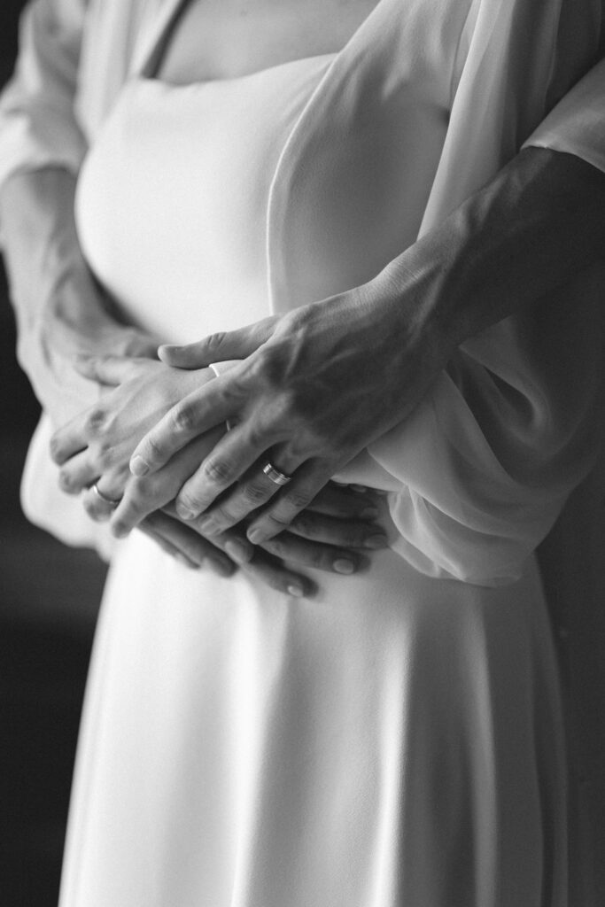 Black and white close-up of the bride's hands resting on her waist.
