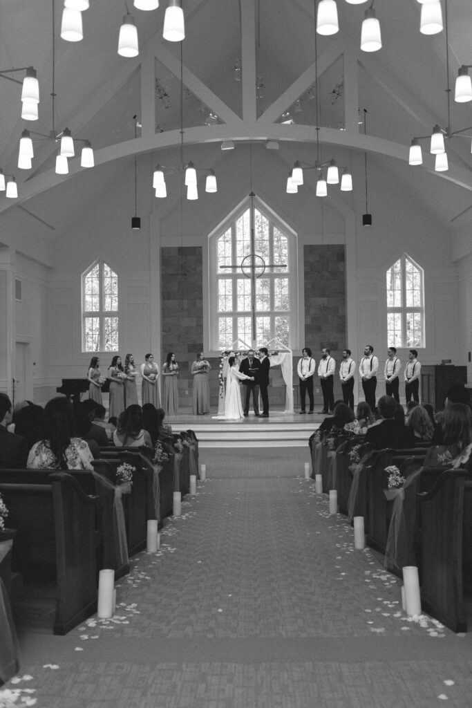 Bride and groom holding hands at the altar, with the officiant speaking.
