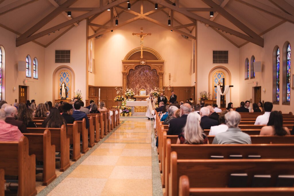 Wide view of the church interior during the wedding ceremony with guests seated.