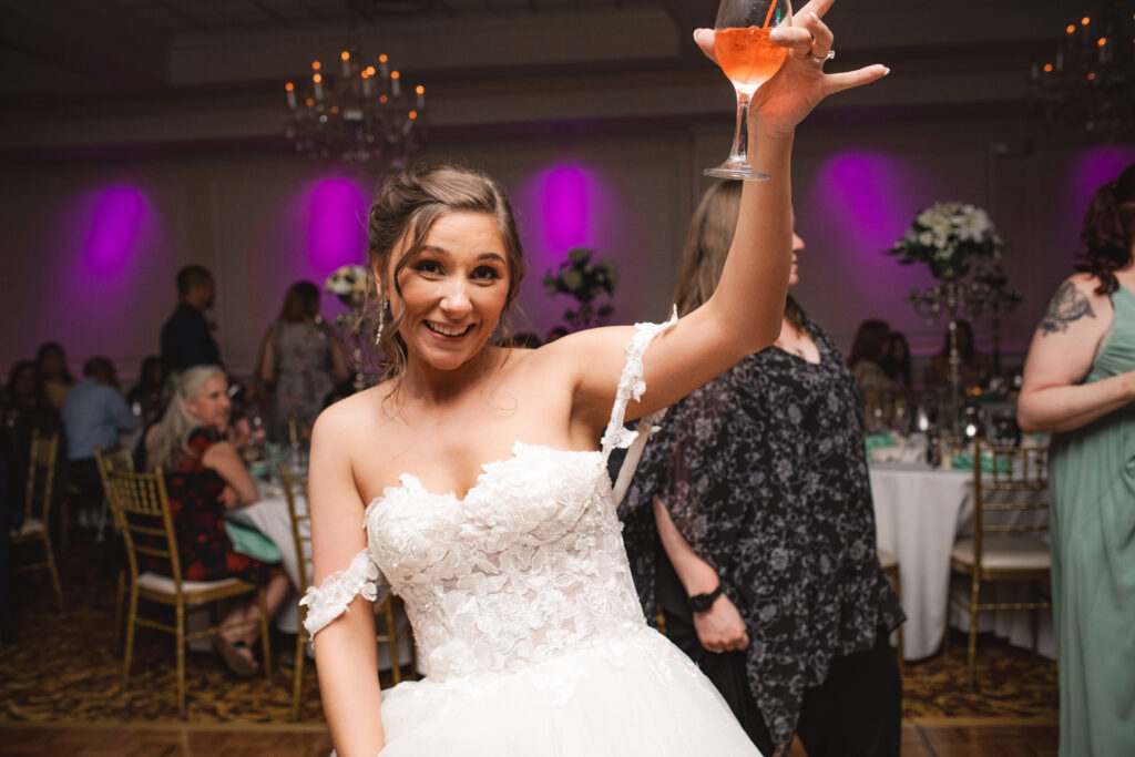 Briana holding up a drink and smiling at the camera during the reception.

