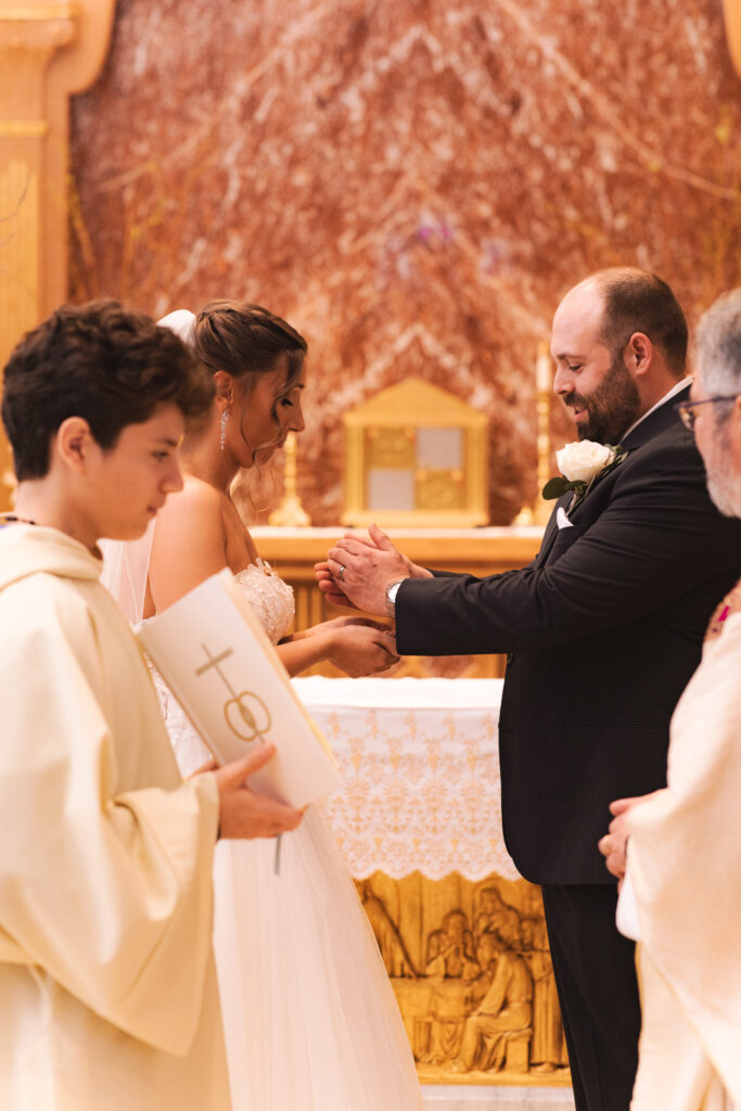 Briana and Pat exchanging rings during their wedding ceremony at the altar.