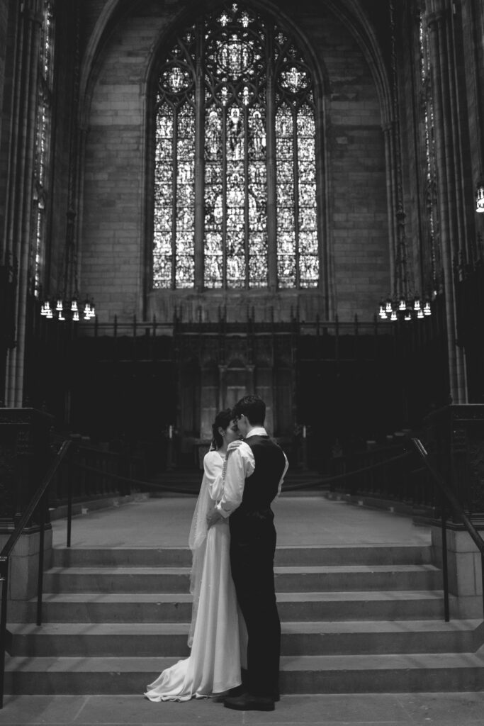 Black and white photo of the bride and groom sharing a kiss in the church.