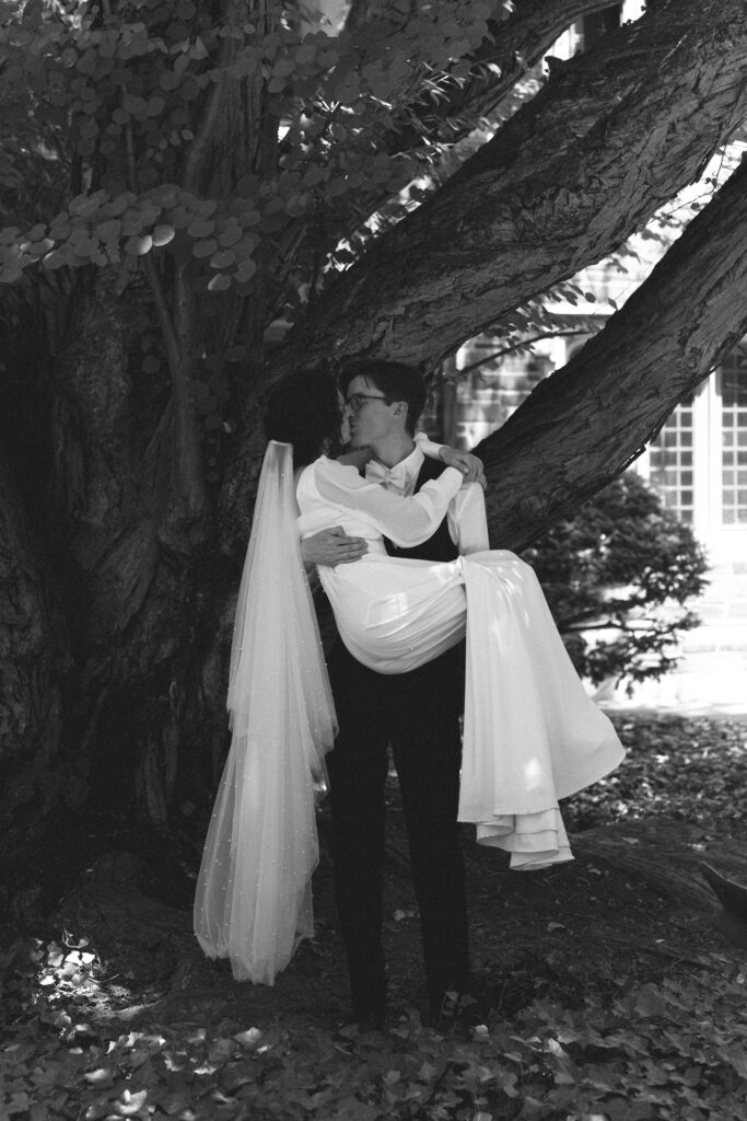 Bride and groom sharing a kiss under a large tree.