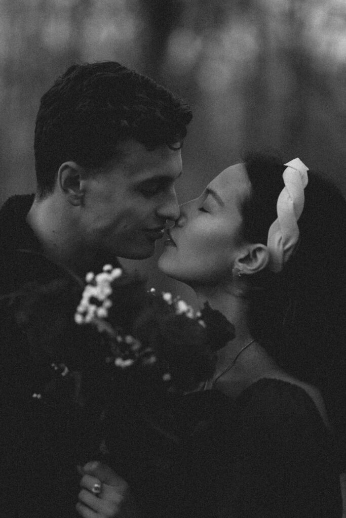 black and white candid photo of a couple kissing with roses. 