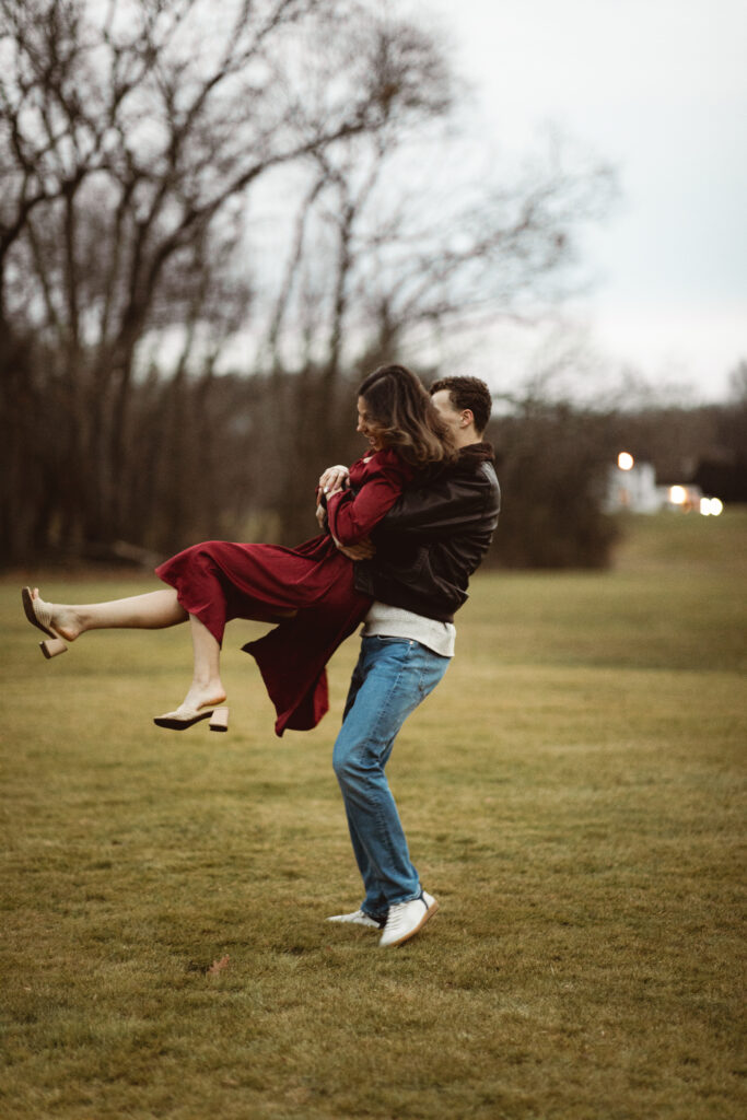 Romantic photo of a couple standing close, with fairy lights in the background.
