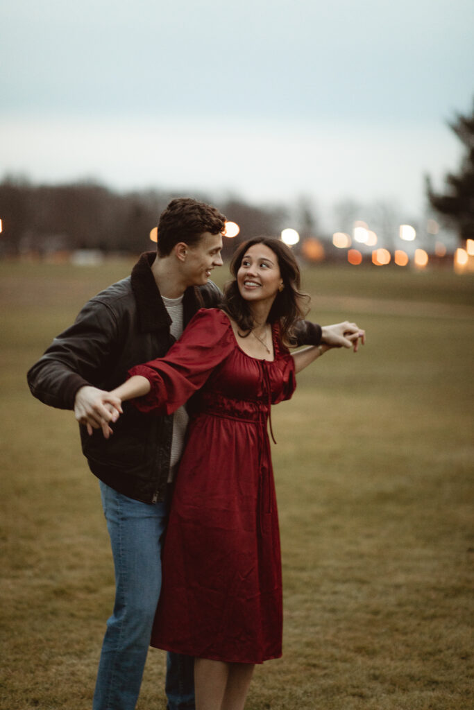 Black and white image of a couple laughing and dancing together outside.
