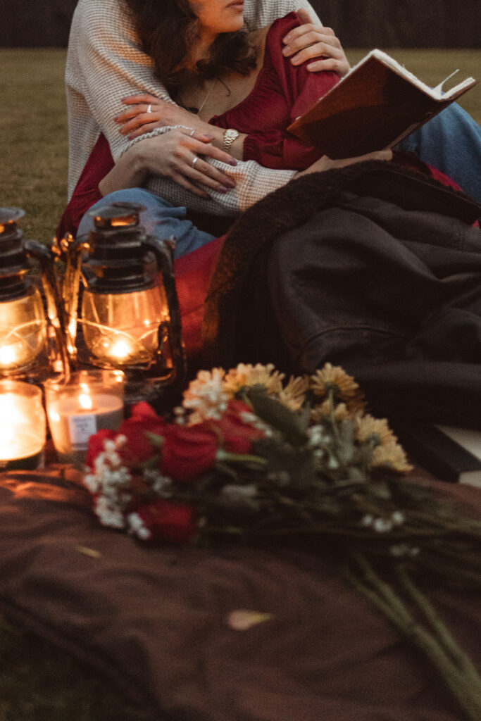 Close-up of a cozy picnic setup with lanterns and flowers, creating a warm atmosphere.
