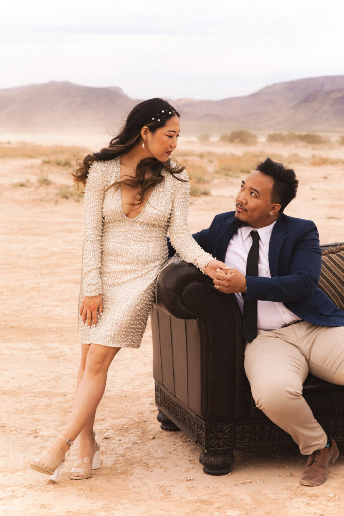 Couple seated on a couch in the desert, sharing a moment during their non-traditional wedding.