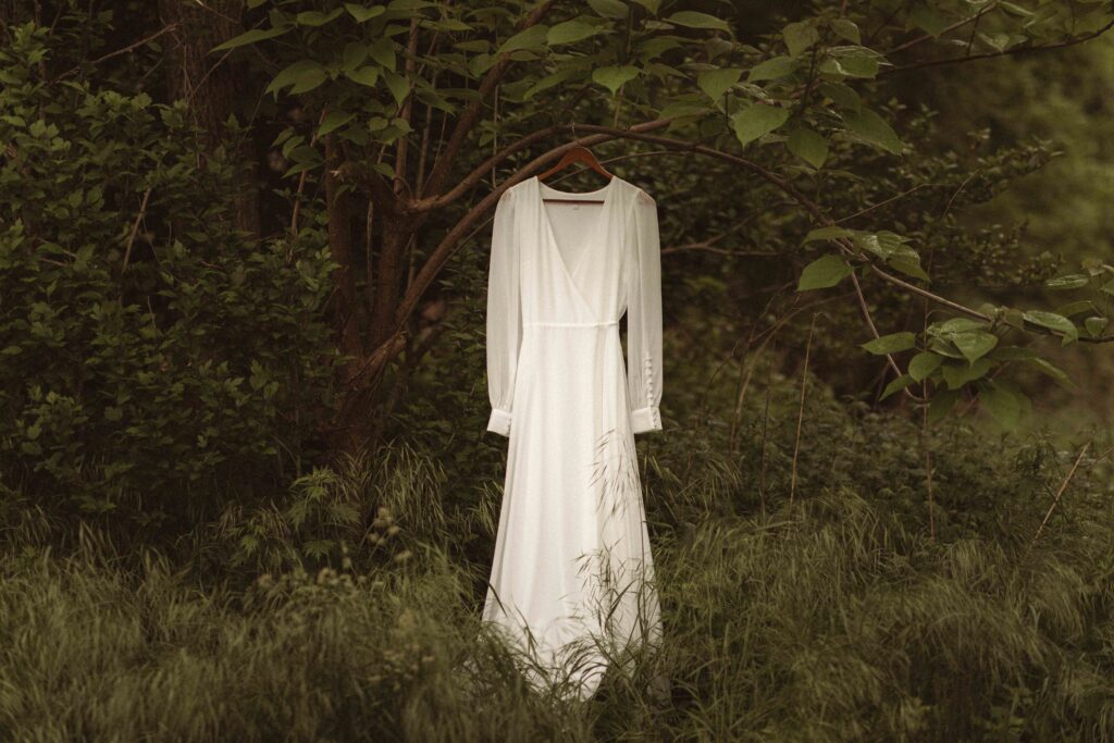 Adventure elopement at Thompson Park in nature with wedding dress hanging on a tree